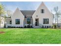 White brick home with a gabled roof, black windows, and a manicured lawn at 131 Evander Way, Pittsboro, NC 27312