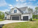 Two-story home featuring a three car garage, stone accents, black shutters, and a well-manicured lawn at 38 Hewitt Woods Dr, Clayton, NC 27527