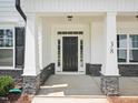Front door with white column pillars and black door at 38 Hewitt Woods Dr, Clayton, NC 27527
