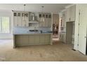 A spacious kitchen features a large island, modern appliances, custom cabinets, and unfinished flooring at 129 Windel Dr, Raleigh, NC 27609
