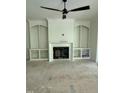 Spacious living room with a fireplace, built-in shelving, ceiling fan, and unfinished floors at 129 Windel Dr, Raleigh, NC 27609