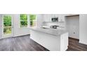 Bright, modern kitchen features a granite island, stainless steel appliances, and wood flooring at 433 Rowe Way, Knightdale, NC 27545