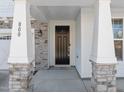 Front entrance with stone pillars, a black door, and a welcoming mat at 800 Summit Crest Ct, Apex, NC 27523