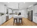 Spacious kitchen features white cabinets, stainless steel refrigerator and appliances, and hardwood floors at 109 Aspenridge Dr, Holly Springs, NC 27540