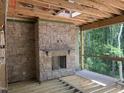 Spacious room with a stone fireplace, unfinished wood floors, and a wall of windows overlooking a wooded landscape at 274 Westhampton Dr, Pittsboro, NC 27312