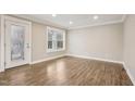 Bright living room with wood laminate flooring, a window, and white trim at 4716 Howe St, Durham, NC 27705