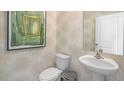 Stylish powder room with pedestal sink, toilet, and decorative wallpaper at 6456 Alfalfa Ln, Wake Forest, NC 27587