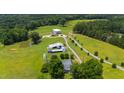 An aerial view of a property showcasing its farmhouse, barns, pond, and surrounding landscape at 14425 Nc-96 N Hwy, Zebulon, NC 27597
