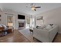 Bright living room featuring a stone fireplace, hardwood floors, ceiling fan and neutral colored furniture at 467 Joseph Alexander Dr, Fuquay Varina, NC 27526