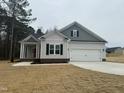 Single-Gathering home boasts a two-car garage, front porch with columns, and freshly laid sod at 100 Preacher Ln, Angier, NC 27501