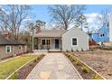 Charming single-story home featuring stone walkway, blue door, covered porch, and beautifully landscaped front yard at 1606 James St, Durham, NC 27707