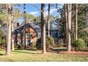 Brick house nestled among tall trees, showcasing its classic architecture at 704 Misty Isle Pl, Raleigh, NC 27615