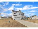 Side view of a white two-story home featuring a two car garage, covered porch and concrete driveway at 8 Looping Horse Cir, Angier, NC 27501