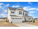 Angle view of a white two-story home with a two car garage, stone-base columns, and covered porch at 8 Looping Horse Cir, Angier, NC 27501