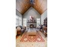 Elegant living room with a stone fireplace, wood-paneled ceiling, and hardwood floors covered with a stylish rug at 101 Bonica Creek Dr, Garner, NC 27529
