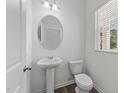 Small bathroom with pedestal sink, toilet, and oval mirror at 148 Babbling Brook Dr, Clayton, NC 27520