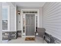 Inviting front entry with gray door, stone accents, and wicker chair at 803 Golden Plum Ln, Zebulon, NC 27597