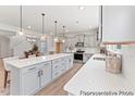 Bright kitchen with stainless steel appliances, gray cabinets, large island, quartz countertops, and pendant lighting at 92 Summer Mist Ln # 164P, Clayton, NC 27527