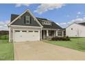 Two-story house with gray siding, white garage doors, and a landscaped yard at 129 Colby Farm Dr, Kenly, NC 27542