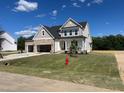 Charming two-story home with stone accents, an attached two-car garage, landscaped lawn, and a neighborhood fire hydrant at 71 Priming Way, Angier, NC 27501