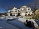 Row of three two-story townhouses with attached garages, snowy landscaping, and wooded background at 133 Walking Path Pl, Hillsborough, NC 27278