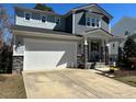 Two-story home with gray siding and stone accents, a large garage door, and a concrete driveway at 1617 Old Bramble Ln, Fuquay Varina, NC 27526