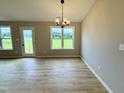 Bright dining room showcasing luxury vinyl plank flooring, modern chandelier and backyard access at 185 N Movado Trl, Kenly, NC 27542