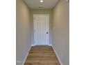 Inviting hallway featuring wood-look flooring and a freshly painted white six panel door at 185 N Movado Trl, Kenly, NC 27542