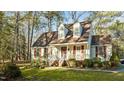 Inviting two-story home with a classic design, red shutters, and a covered front porch nestled among tall trees at 1909 Pearces Rd, Zebulon, NC 27597