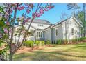 Rear exterior view showcasing gray siding, manicured landscaping, and a screened-in porch, offering a serene outdoor space at 2721 Sanctuary Woods Ln, Raleigh, NC 27606