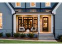 Inviting front porch featuring stylish seating, a dark-stained front door, and a well-maintained lawn with trimmed bushes at 2721 Sanctuary Woods Ln, Raleigh, NC 27606