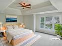 Serene main bedroom boasts a tray ceiling, a ceiling fan, and a large window at 408 Froyle Ct, Rolesville, NC 27571