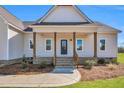 Inviting front porch with wooden columns, brick base, and charming curb appeal on a sunny day at 1178 Sheriff Johnson Rd, Lillington, NC 27546