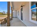 Covered porch featuring wooden pillars, a black front door, and exterior lighting at 1178 Sheriff Johnson Rd, Lillington, NC 27546