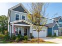 Two-story house with gray and light green siding, a white double garage door, and landscaping at 166 Retreat Dr, Fuquay Varina, NC 27526