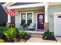 Charming front porch with purple door, brick columns, and comfortable seating at 166 Retreat Dr, Fuquay Varina, NC 27526