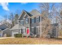 Two-story gray house with a red door, white garage door, and landscaping at 300 Ashwick Dr, Efland, NC 27243