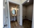 Bathroom with a pedestal sink and wood-look floor plus a view of the laundry room at 14 E American Marigold Dr # 65, Benson, NC 27504