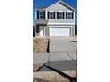 A gray two-story home features a two-car garage, black shutters, and a newly installed concrete driveway and sidewalk at 340 Arch Canyon Cir, Zebulon, NC 27597