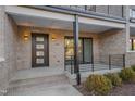 Townhouse entry with brick facade, dark door, and small patio at 1016 Manor Way, Durham, NC 27701