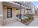 Inviting townhome porch with brick steps, dark metal railings, a door with glass, and modern lighting at 1016 Manor Way, Durham, NC 27701