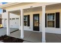 Inviting covered front porch with white columns, number 101, black shutters, and view of the garage at 107 Barn Door Dr, Lillington, NC 27546