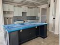 Spacious kitchen featuring white cabinets, dark island, and mosaic backsplash at 107 Barn Door Dr, Lillington, NC 27546