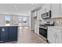 Modern kitchen with stainless steel appliances, sleek white cabinets, and a large blue kitchen island at 107 Barn Door Dr, Lillington, NC 27546