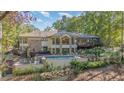 Stunning rear exterior view features a stone facade, large windows, a swimming pool, and a deck at 12044 Iredell, Chapel Hill, NC 27517