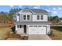 Attractive gray two-story home featuring a two-car garage, well manicured lawn, and blue skies above at 48 Railcar Way, Clayton, NC 27520