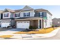 Attractive townhouse with a two-car garage, brick details, and modern light gray and dark gray facade at 931 Haybeck Ln, Apex, NC 27523