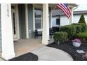 Inviting covered porch with seating area and attractive landscaping including a flag display at 104 Warm Wood Ln, Apex, NC 27539