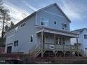 Two-story light blue house with a front porch and a side view of the garage at 1203 Chaney Rd, Raleigh, NC 27606