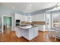 Bright kitchen with white cabinets, granite countertops, kitchen island with cooktop, stainless steel appliances, and hardwood floors at 430 Federal Rd, Benson, NC 27504